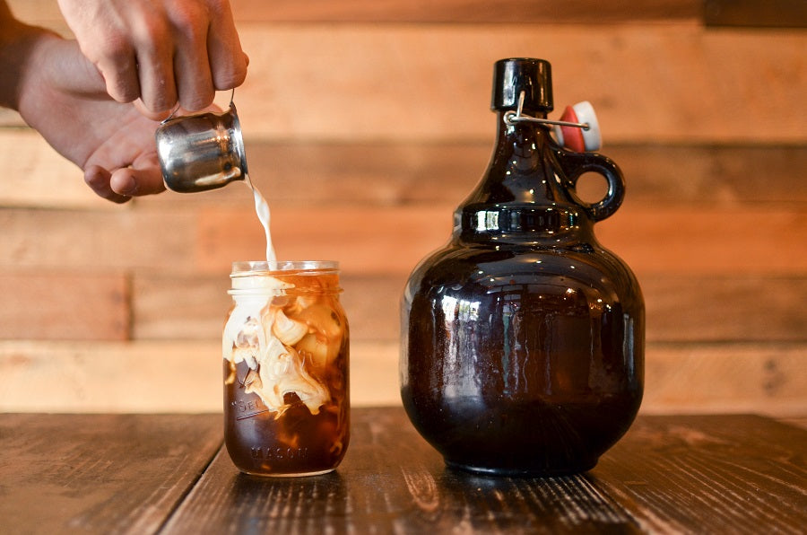 Growler of Toddy next to a cup of toddy with milk