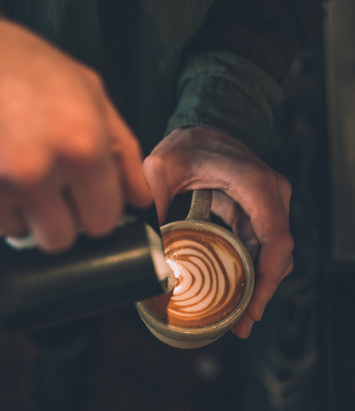 pouring steamed milk into cup with espresso