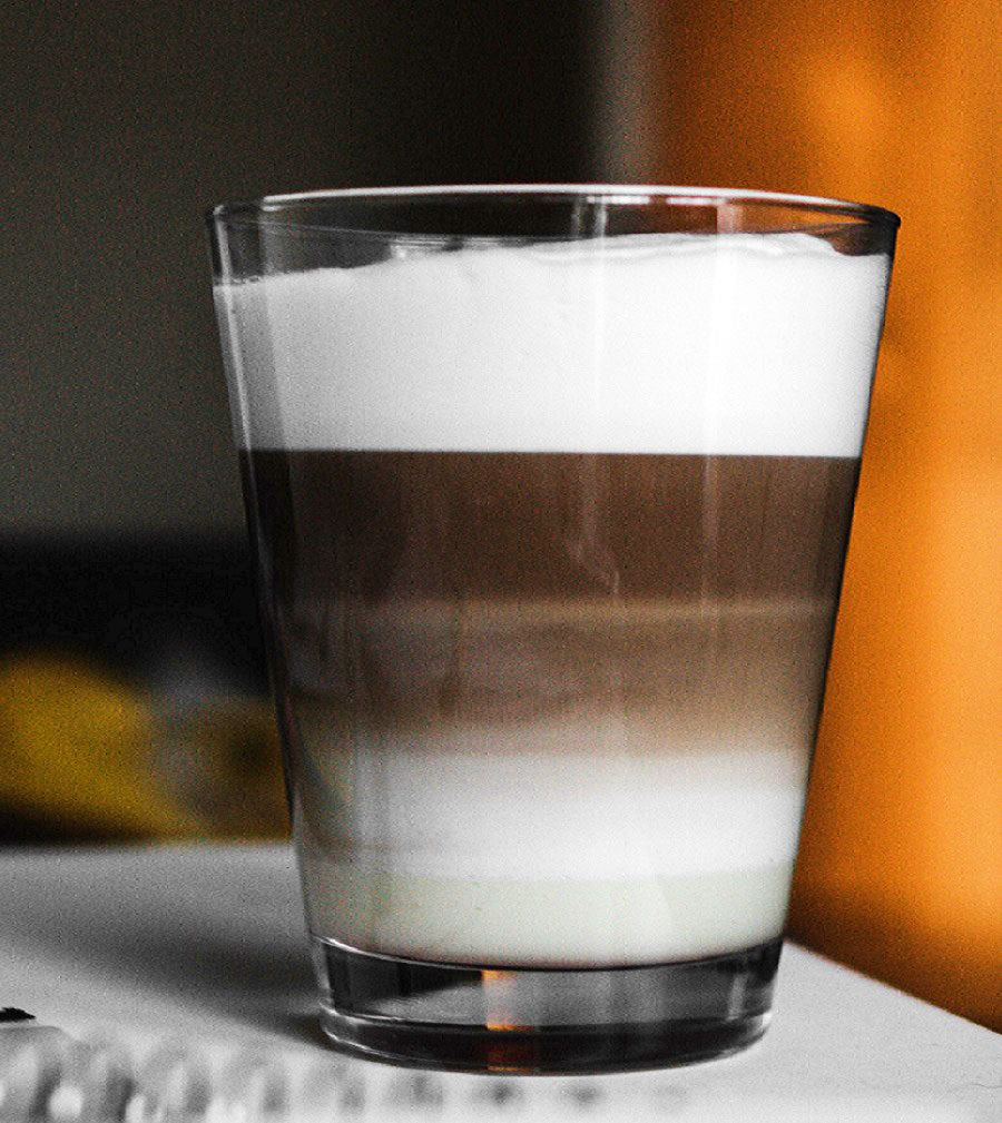 A clear glass illustrated the 3-part ratio of a traditional cappuccino