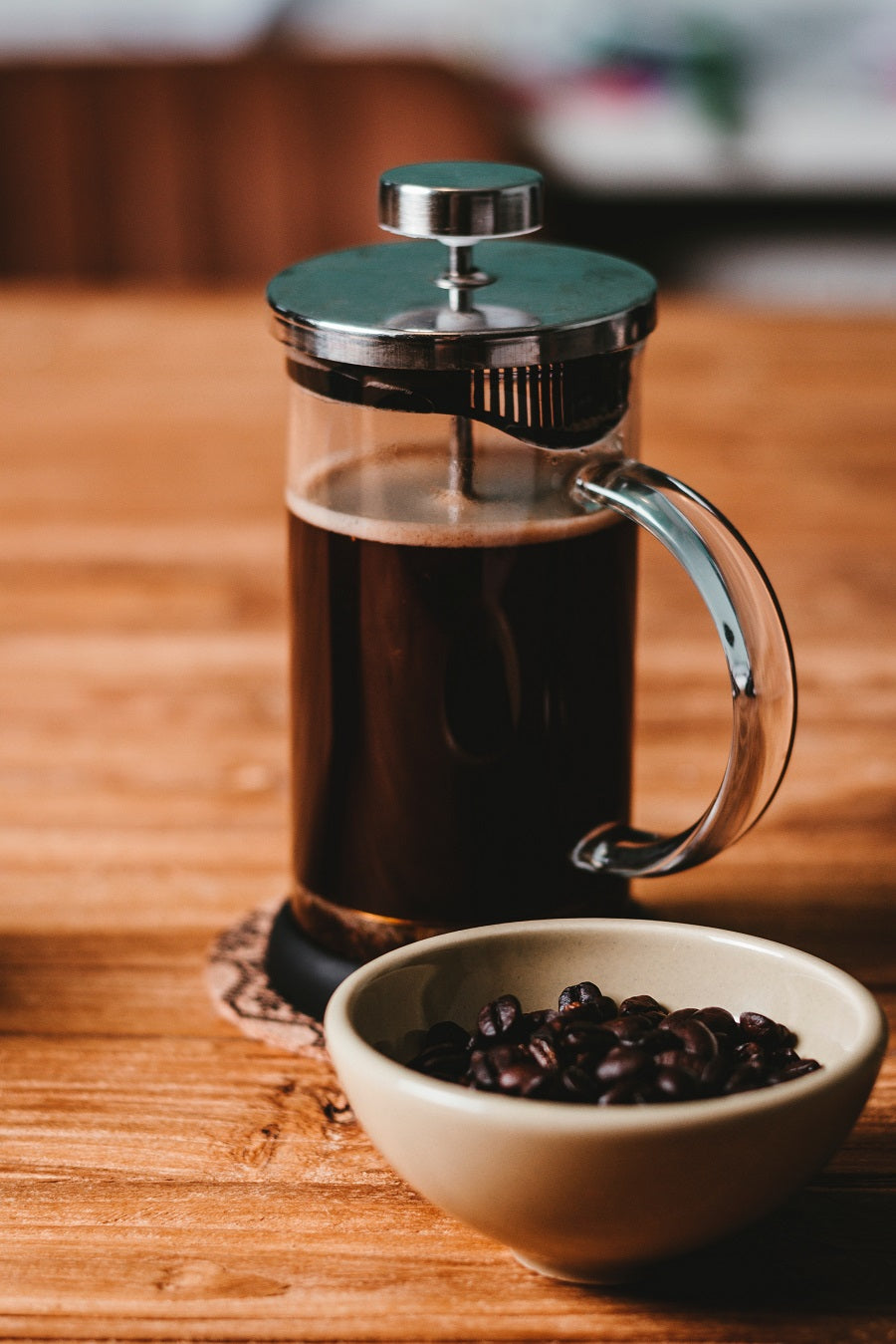 French Press next to white bowl with coffee beans in it