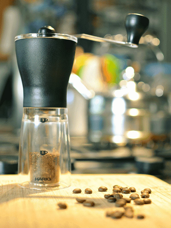 How to Choose a Coffee Grinder - A photograph depicting a Hario Mini Mill manual grinder standing on a kitchen counter top