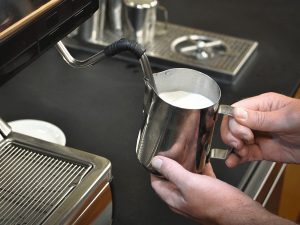 milk is steamed in a stainless steel pitcher using the steam-wand attached to the side of an espresso machine