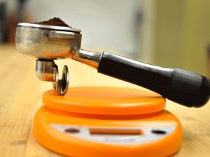 a portafilter loaded with coffee sits on a kitchen scale